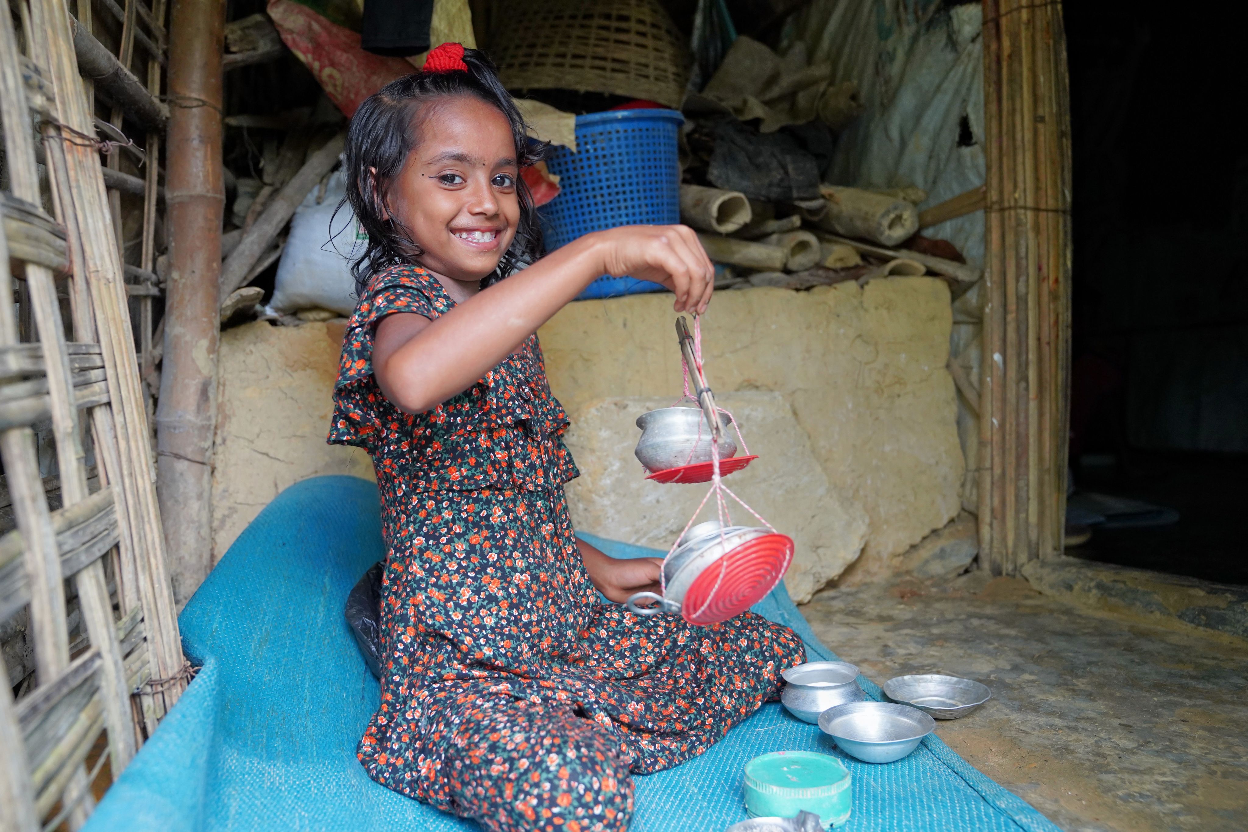 Sultana*, 7, plays with small spice containers in her family's kitchen in Cox's Bazar, Bangladesh